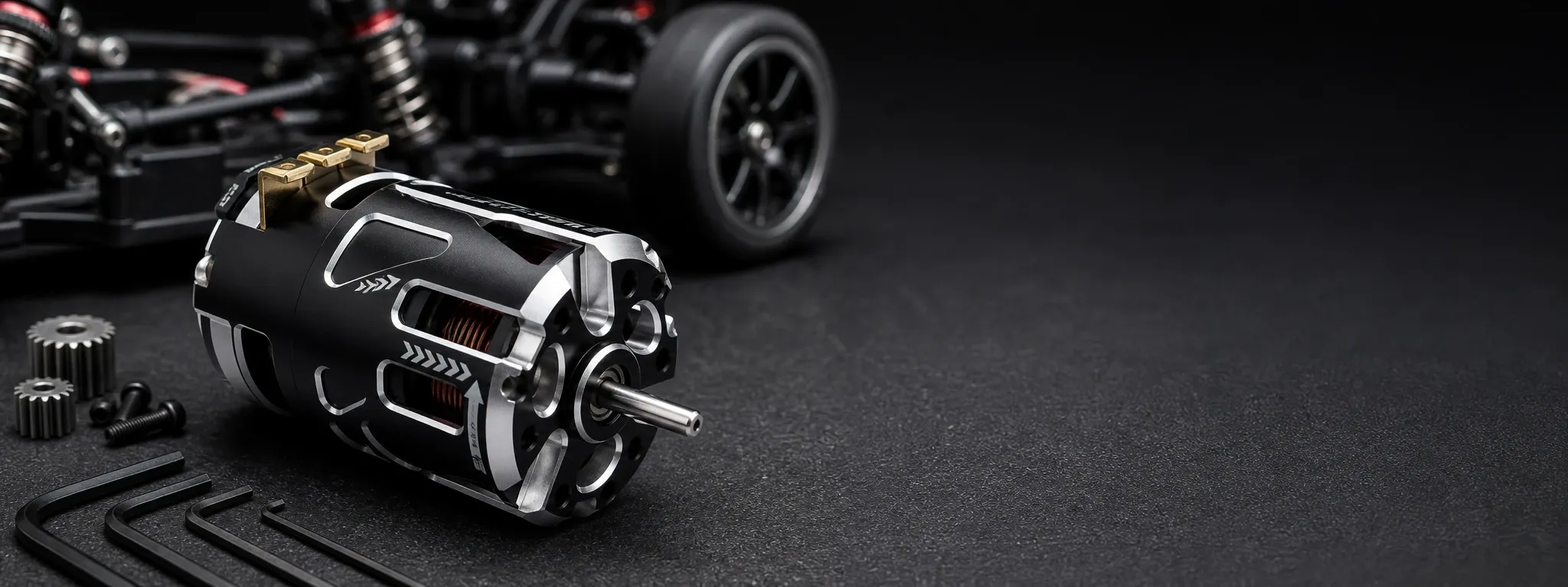 Black and silver 540 brushless RC motor with exposed copper windings, shown in a studio-style motorsport setup beside RC car components and tools.